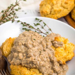 Biscuits and gravy on a plate with fresh thyme