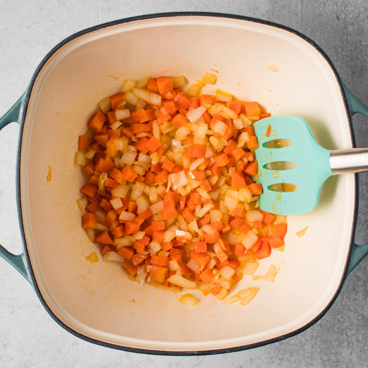 Carrots and onions sautéing in a pot.