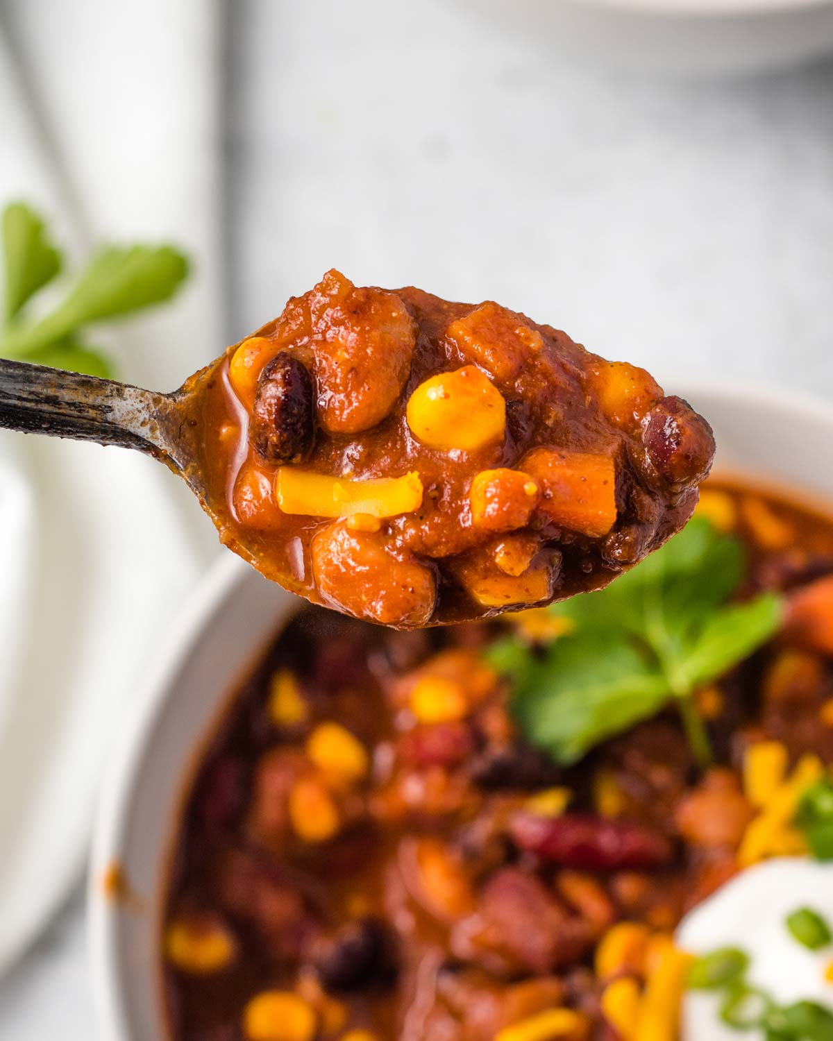 A spoonful of vegan chili with beans, carrots, and corn.
