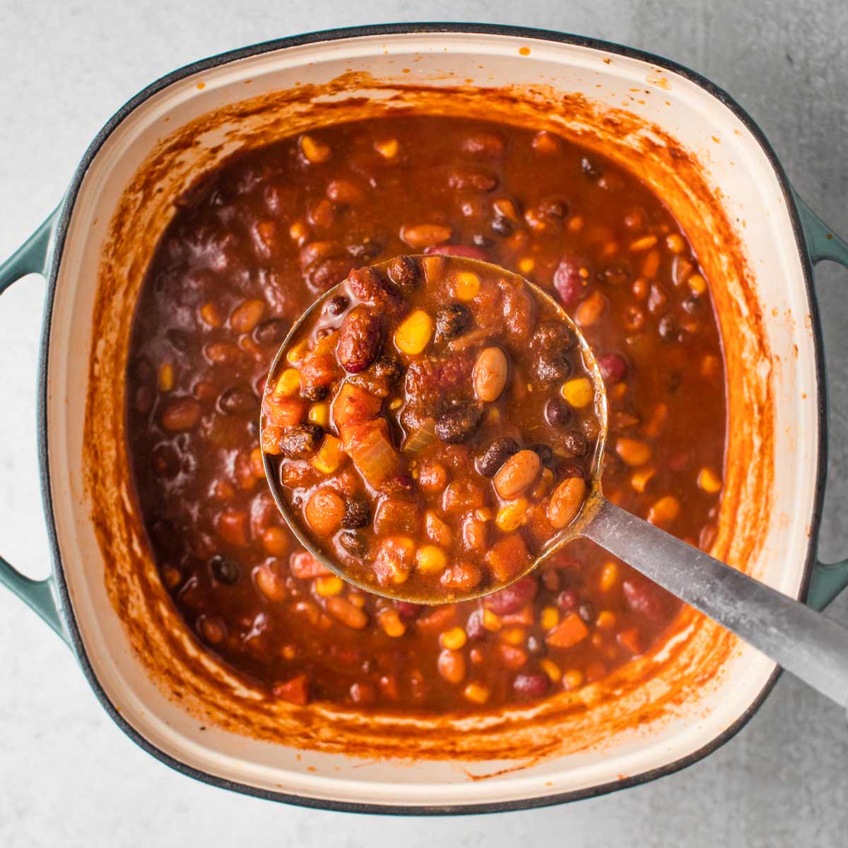 Finished pot of vegan chili, with a ladle taking a scoop out.