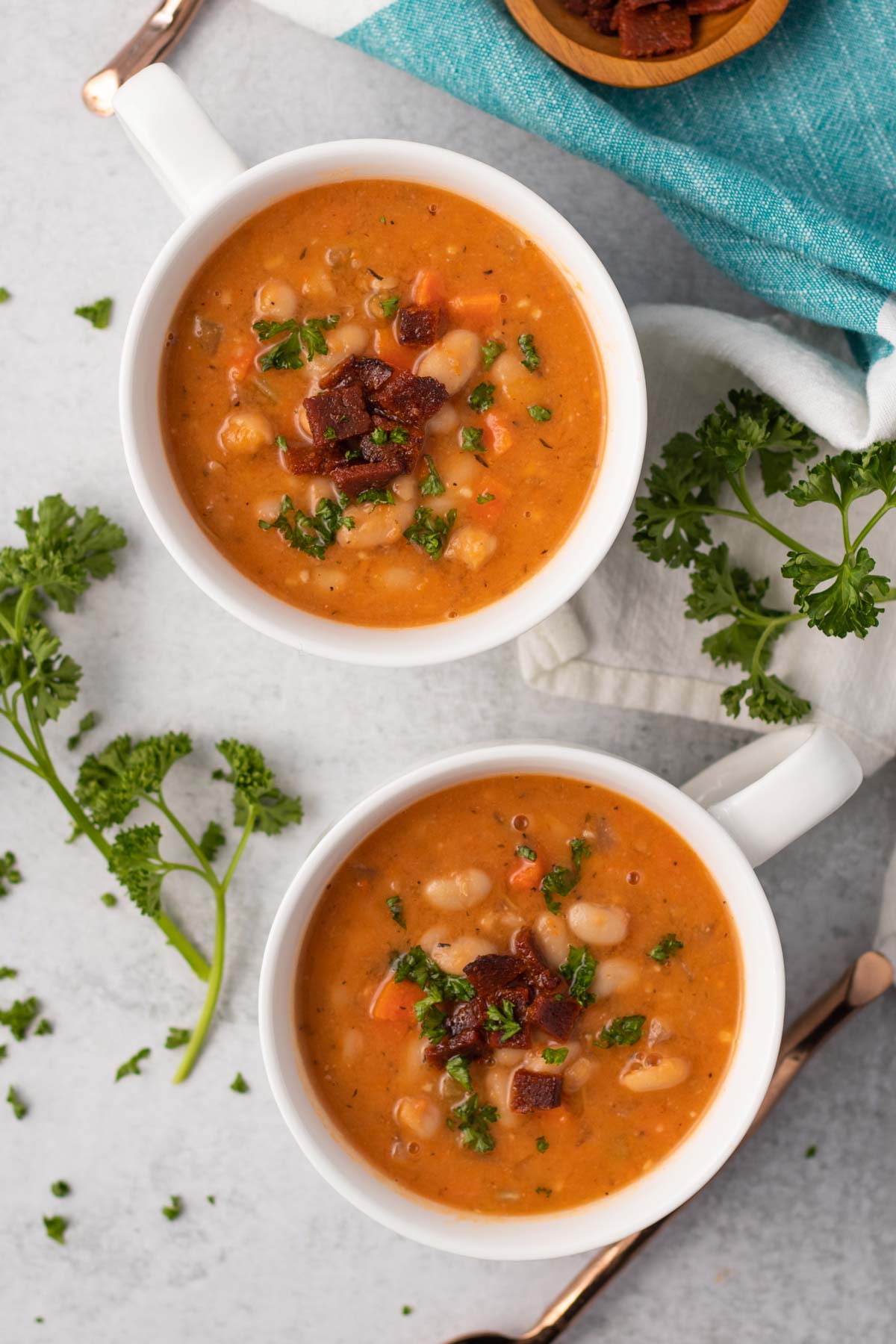 two bowls of vegan bean and bacon soup with tomato sauce
