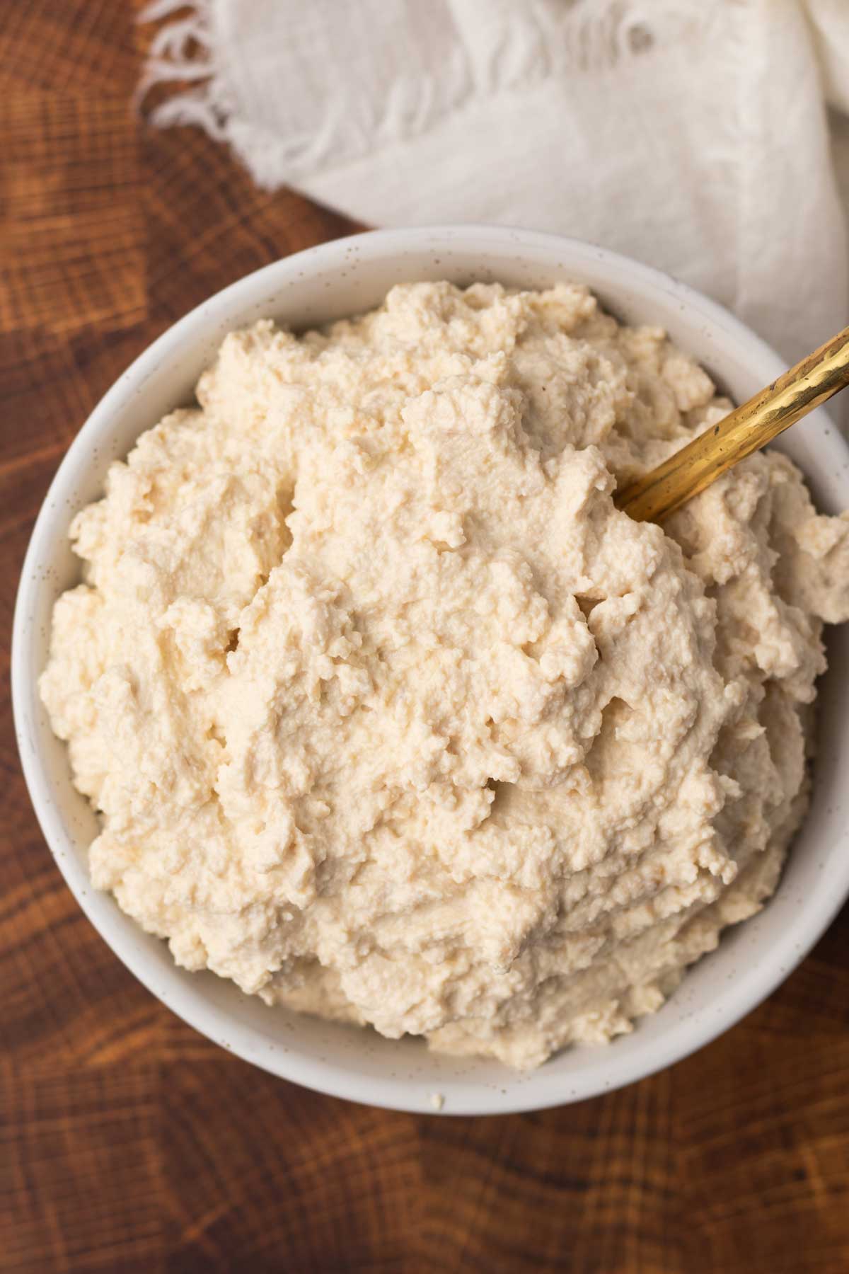 bowl of ricotta cheese with a wooden spoon