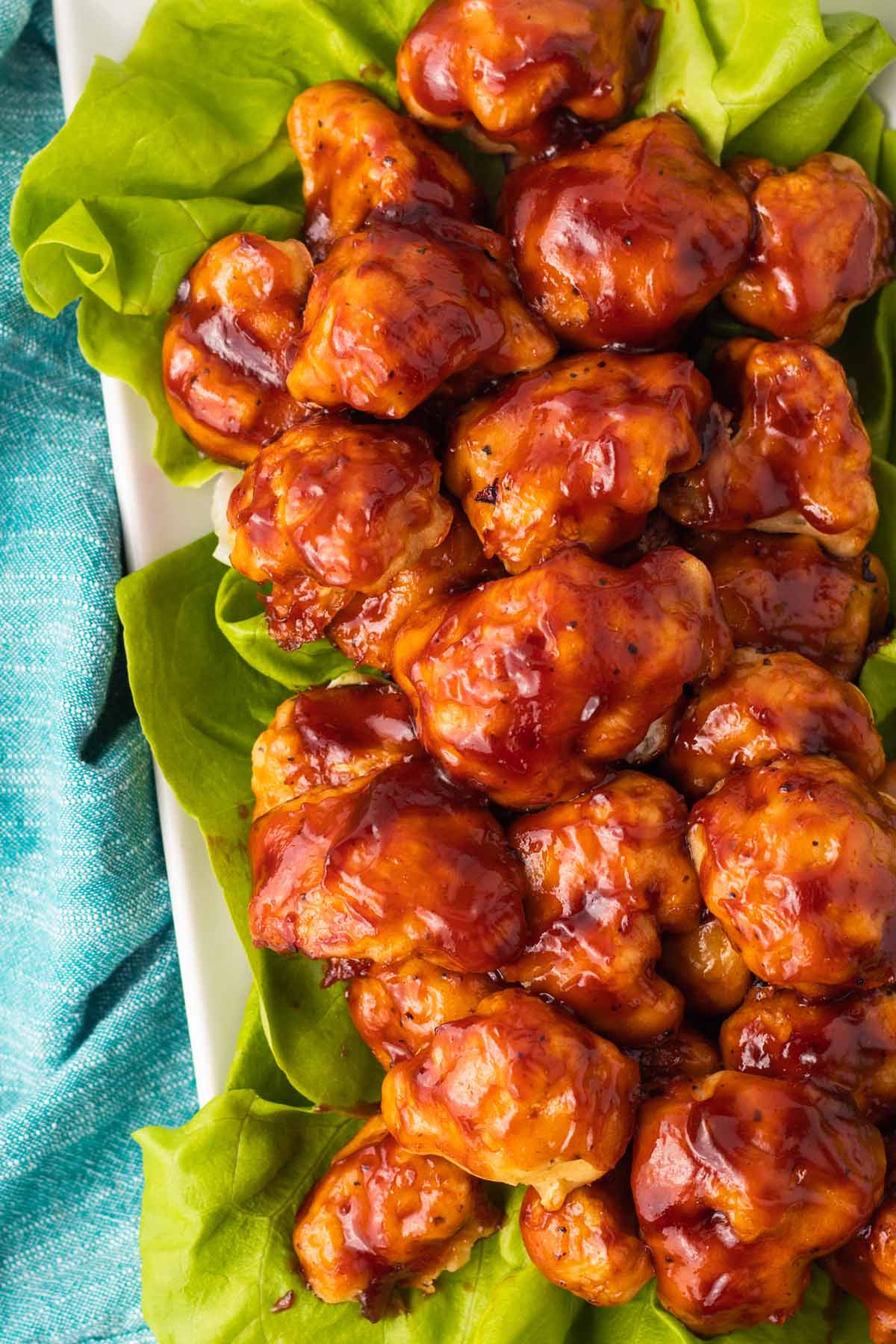 close up on bbq cauliflower wings on a plate with lettuce leaves