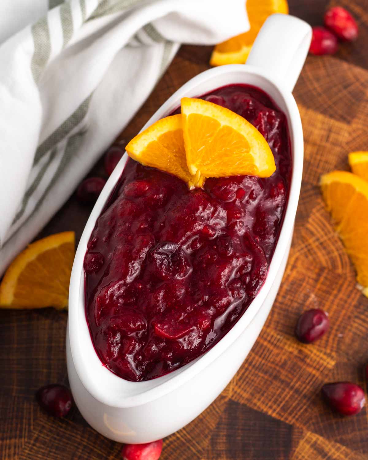 Cranberry sauce in a gravy boat garnished with orange slices.